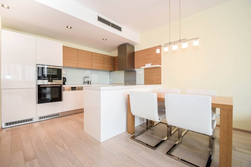 A kitchen with white cabinets, a dining table, and a wooden decor floor in a 3-room apartment.