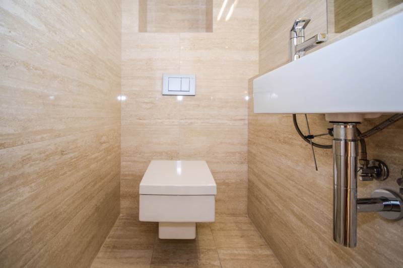 A bathroom in a 3-room apartment with a toilet and tasteful beige tiles.