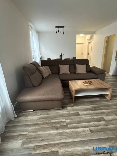 A comfortable living room with a brown sofa and a table, floor with wood decor.