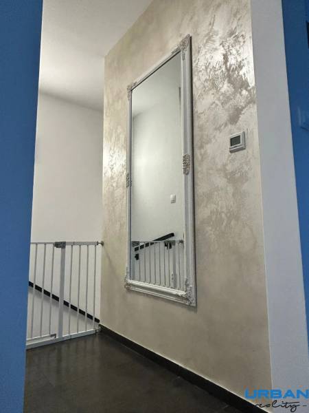 A hallway with a mirror and a safety gate in a 3-room apartment.