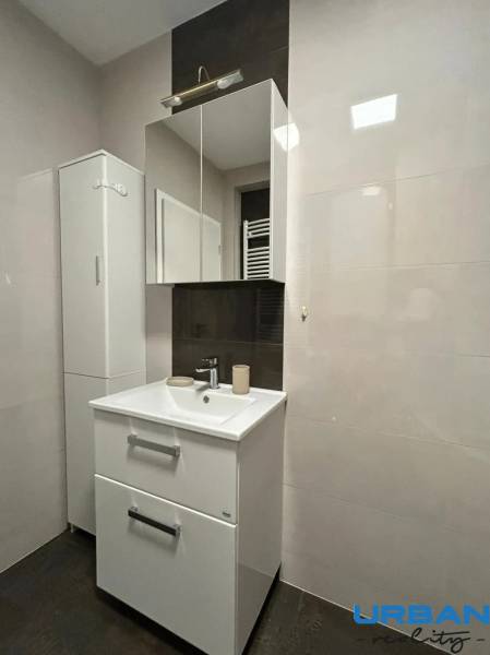 A bathroom in a 3-room apartment with white cabinets and a sink.
