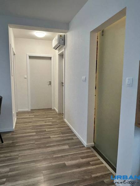 A hallway in a 3-room apartment with a wooden decor floor and air conditioning.