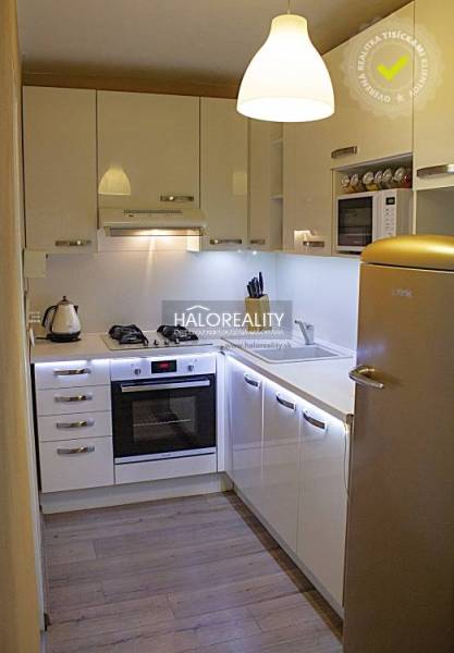 A kitchen in a 2-room apartment with white cabinets and a wood-patterned floor.
