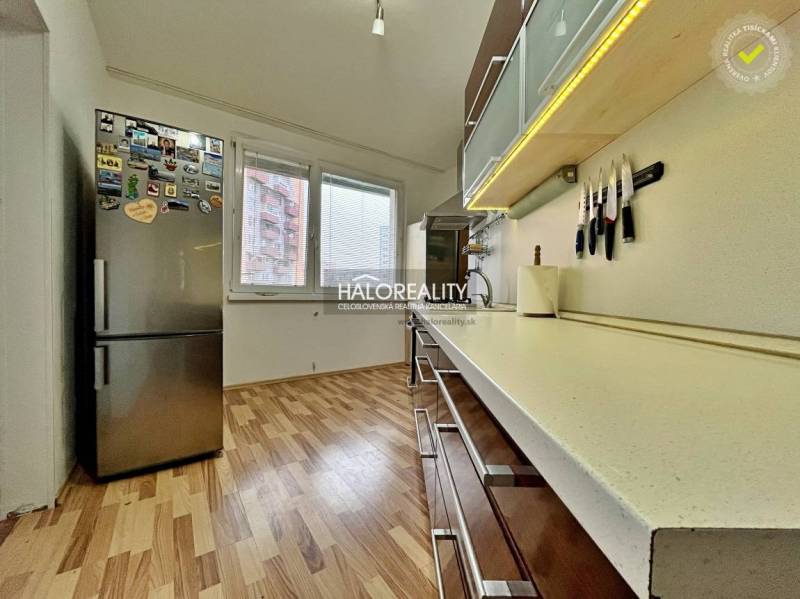 The kitchen of a 3-room apartment with a wooden decor floor and modern appliances.