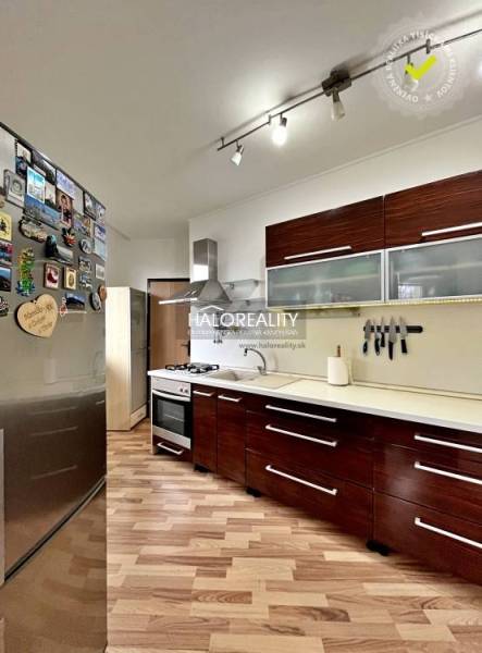 A kitchen in a 3-room apartment with a wood-patterned floor and appliances.