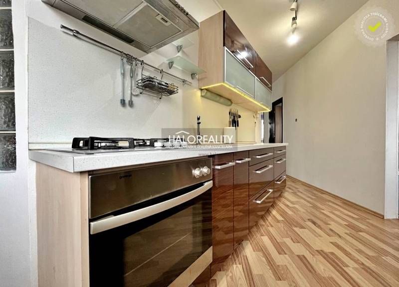 A kitchen in a 3-room apartment with a modern kitchen unit and a floor with a wooden decor.
