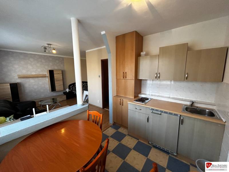 A kitchen with a dining table in a studio apartment, floor with wood decor.