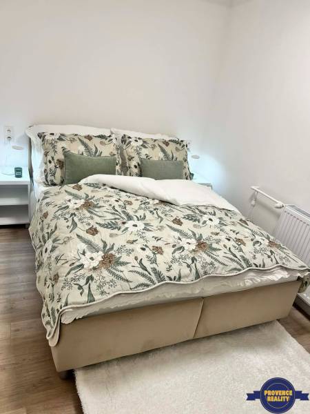 A bedroom in a 2-room apartment with floral bedspreads and a wooden decor floor.