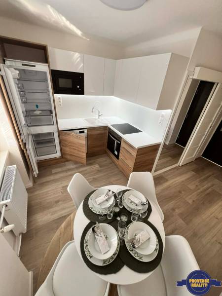 A kitchen in a 2-room apartment with a wooden decor floor and a dining table.