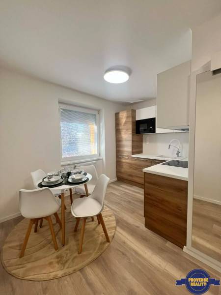A kitchen in a 2-room apartment with a table, chairs, and a wooden decor floor.