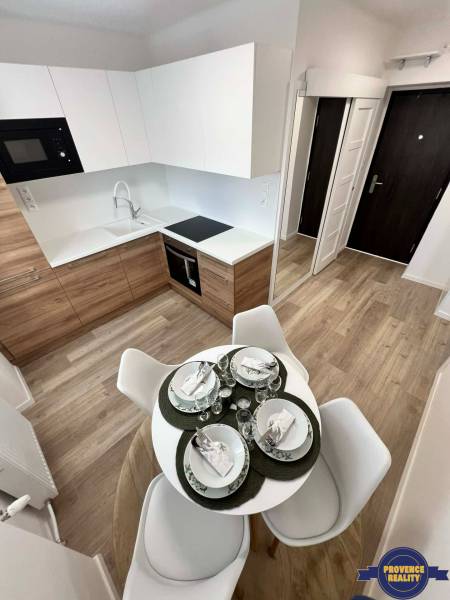 A kitchen in a 2-room apartment with a wood-patterned floor and a dining table.