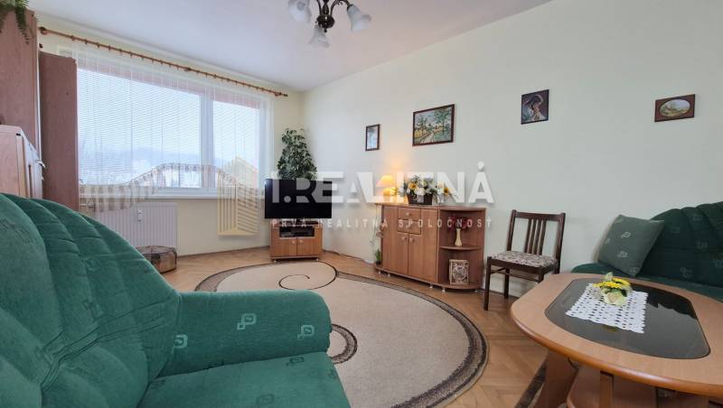 A living room with wood-patterned flooring, a green sofa, and furniture in a two-room apartment.