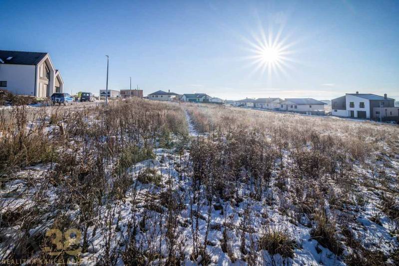 A snowy plot in Mlynica with dwellings in the background, ideal for living.