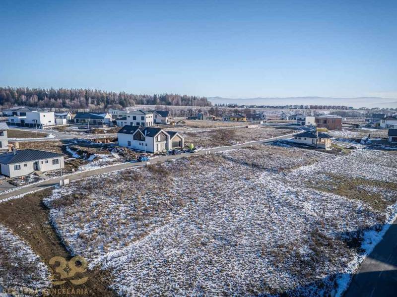 Plots - housing in Mlynica with a view of snow-covered mountains and houses on the slope.