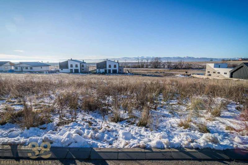 Snow-covered residential plots in Mlynica with sunny weather and visible houses in the background.