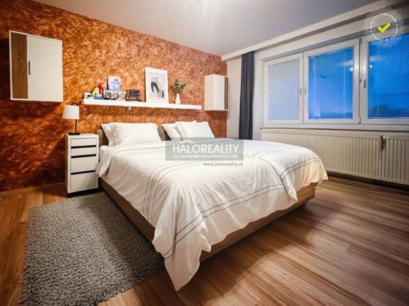 Bedroom in a two-room apartment with a wood-patterned floor and an orange wall.