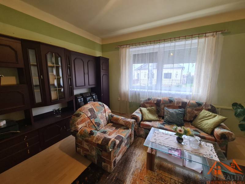 A living room of a family house with a colorful couch and a dark wall unit.