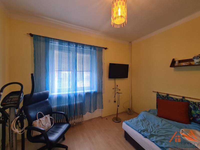 A room in a family house with exercise equipment, a chair, and a television.