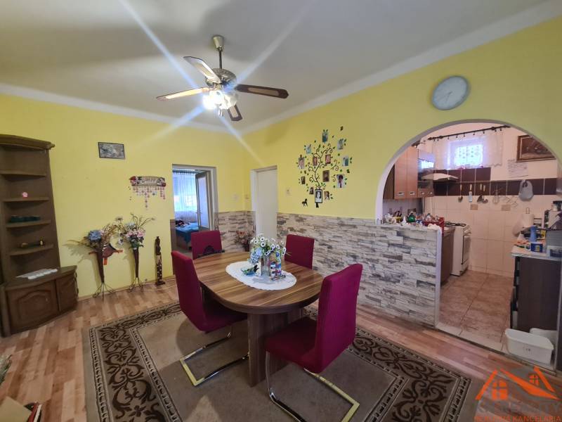 Dining room in a family house with a round table, chairs, and a wooden decor floor.