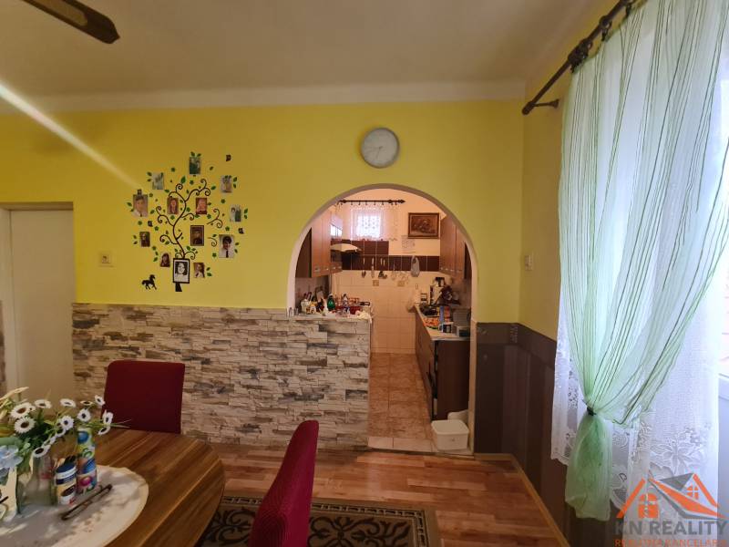 A dining room in a family house with an arched passage and a wooden decor floor.