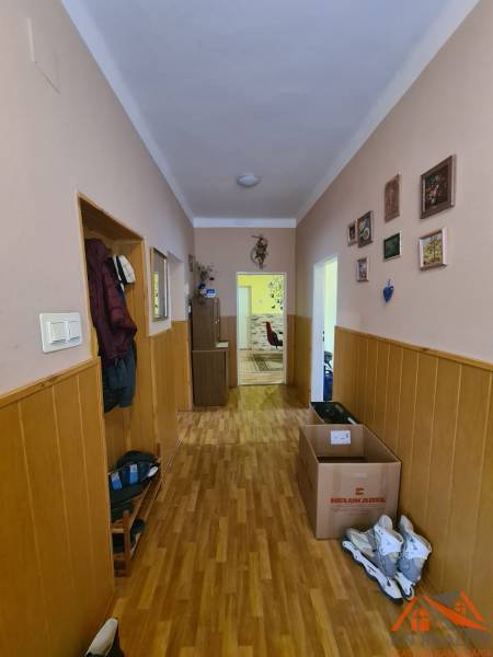 A hallway with a wooden decor floor, walls adorned with paintings in a family house.