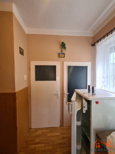 Interior of a family house with two doors, a refrigerator, and a wooden decor floor.