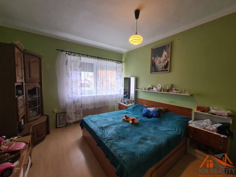 A bedroom in a family house with a wooden decor floor and a bed.