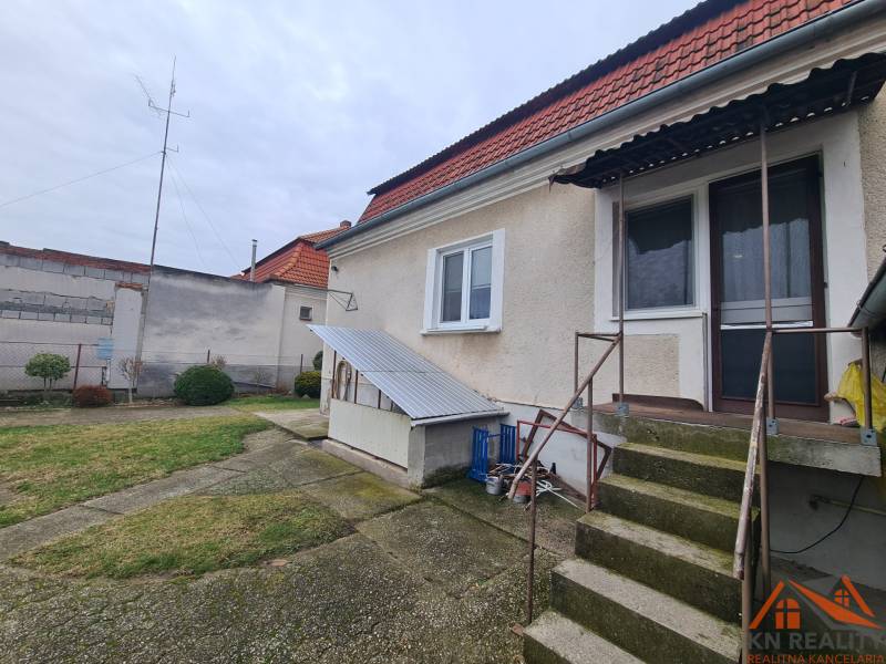 A family house in Hurbanovo with a terrace and garden, with fencing and trees in the background.