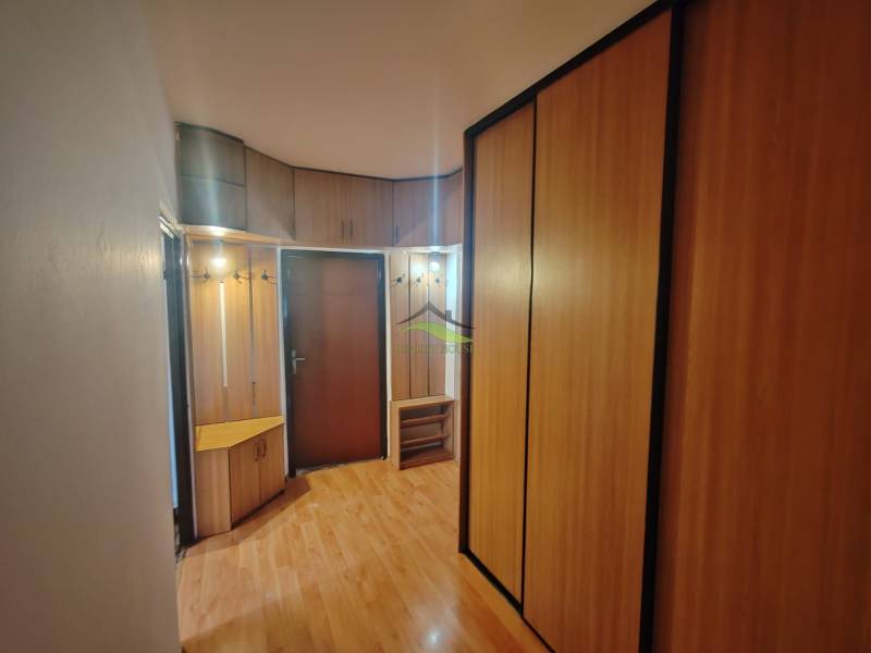 Entrance hallway in a 3-room apartment with a wooden decor floor and built-in wardrobes.