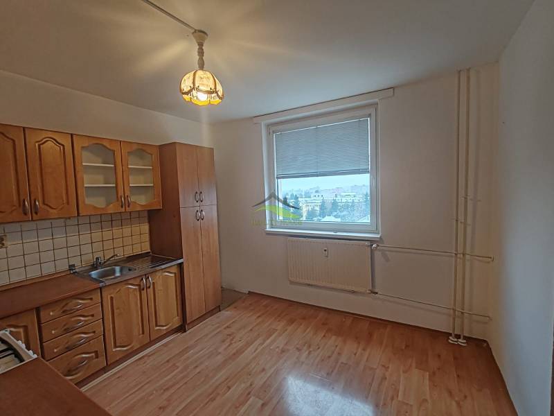 A kitchen with a wooden floor decor in a 3-room apartment with white walls and classic cabinets.