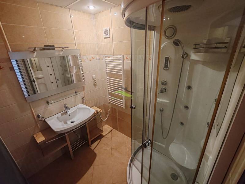 Bathroom in a 3-room apartment with a corner shower, mirror, and sink.