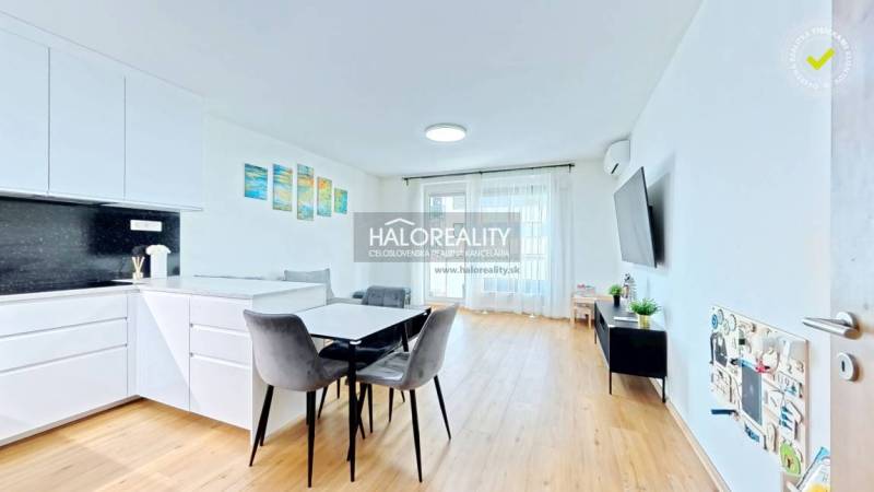 Interior of a 2-room apartment with a kitchenette, dining area, and wooden decor flooring.