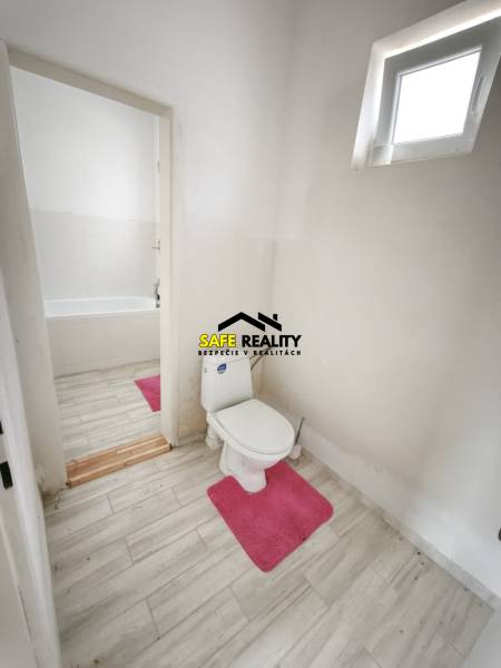 Bathroom in a family house with a toilet, bathtub, and floor with a wooden decor.