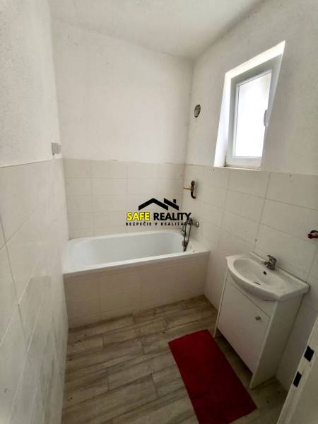 A bathroom in a family house with a bathtub, a sink, and a floor with a wooden design.