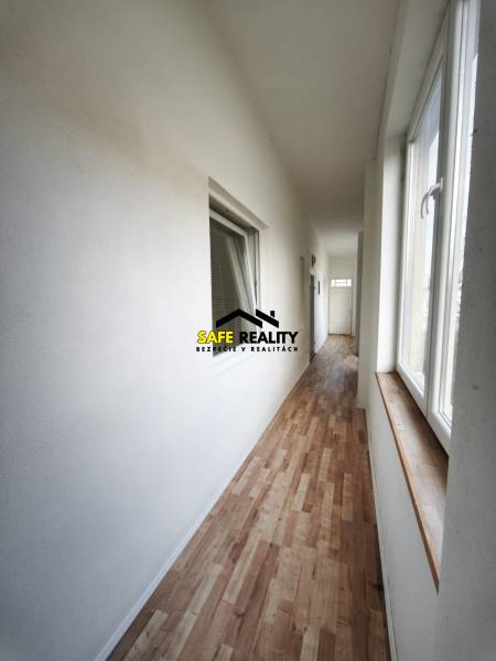 A hallway in a family house with a wooden decor floor and large windows.