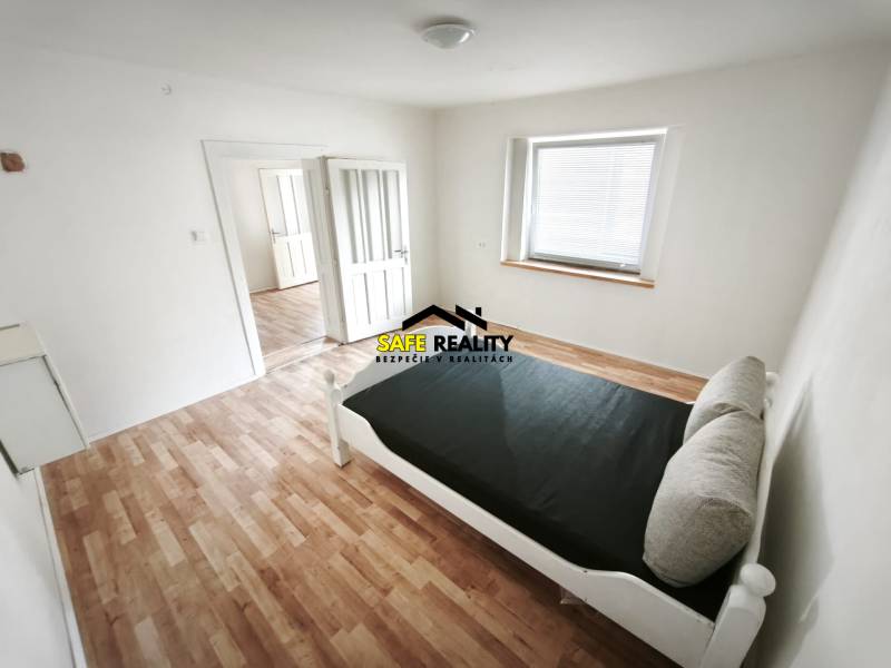 A bright room with a bed, a floor with wood decor, in a family house.