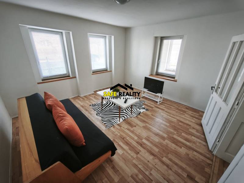Living room in a family house with a sofa, television, and wooden decor flooring.