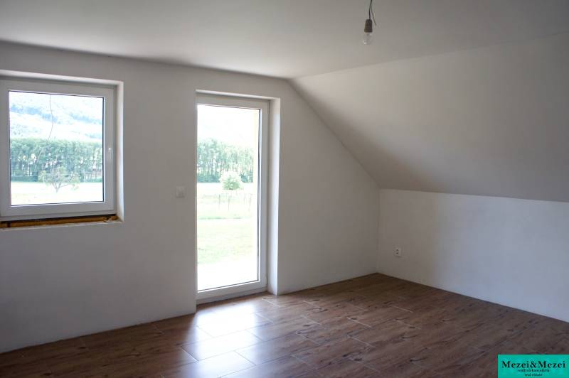 A bright room with windows, a wooden decor floor, and glass doors in a family house.