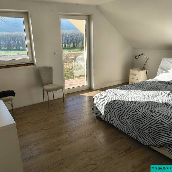 Bright bedroom in a family house with a bed, chair, and wooden decor flooring.