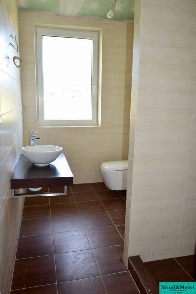 A bathroom in a family house with a light sink and a wooden decor floor.