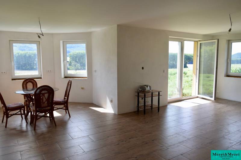 Interior of a family house with a wooden decor floor, windows, and furniture.