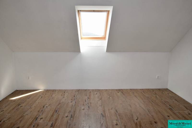 Attic room with a window and a wooden decor floor in a family house.