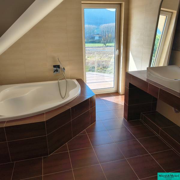 A family house bathroom with a bathtub and a wooden decor floor.
