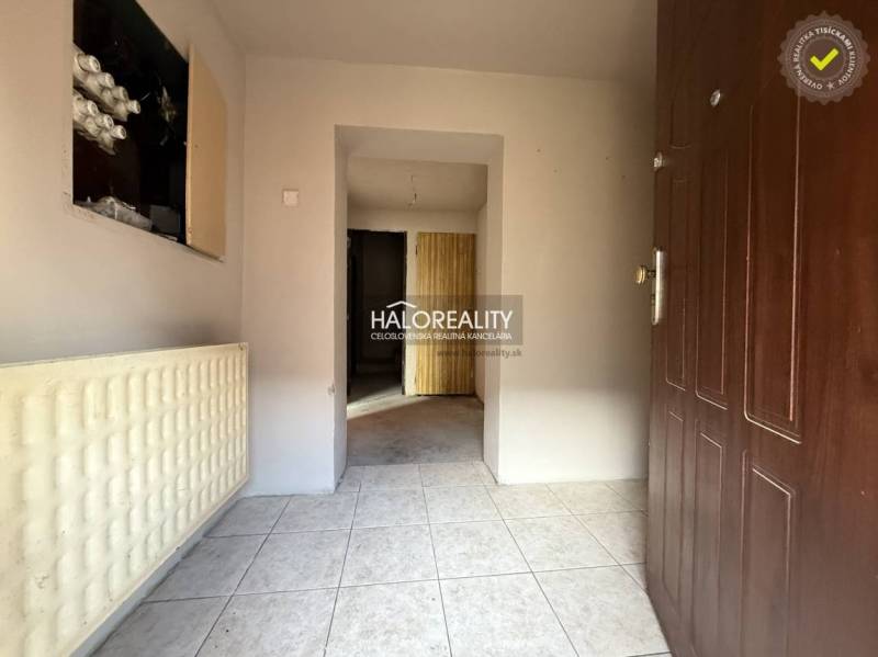 Entrance hallway of a family house with white tiles and brown doors.