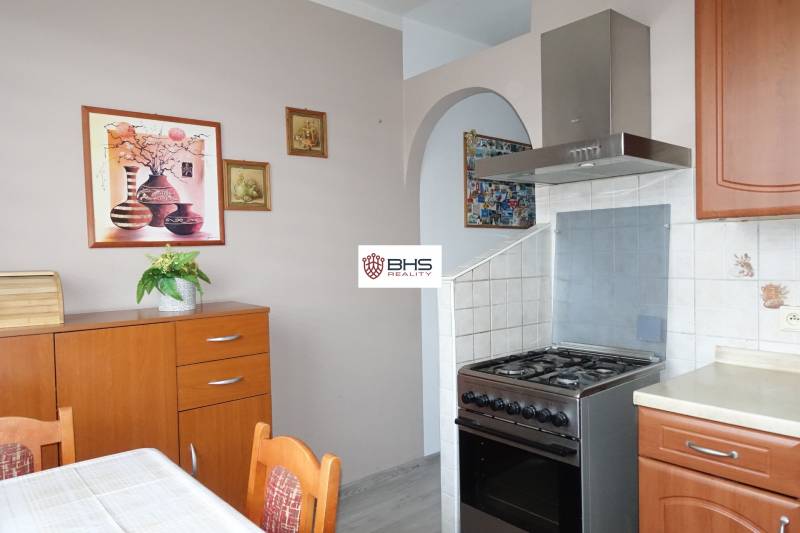 A kitchen in a 3-room apartment with a gas stove and wooden decor furniture.