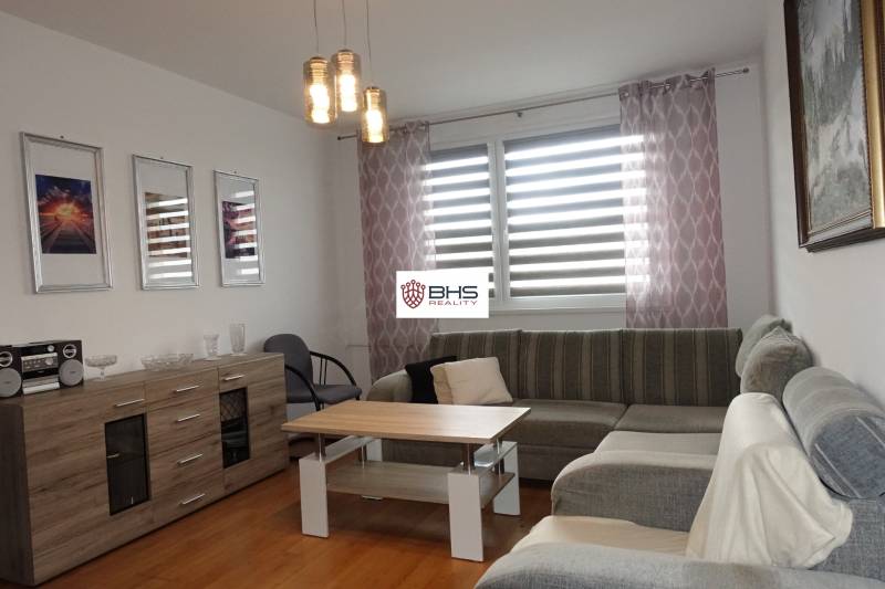 A bright living room with a corner sofa, a coffee table, and a sideboard in a three-room apartment.