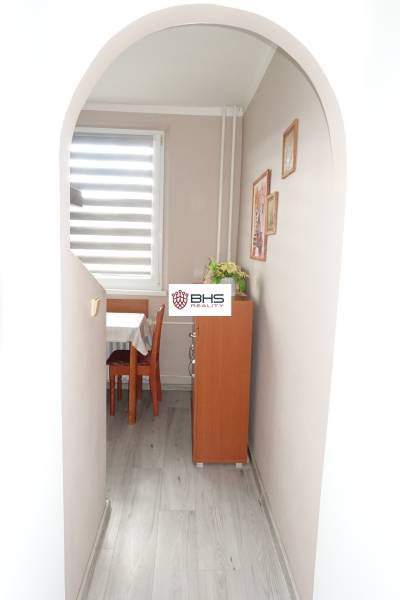 A hallway with an arched entrance and a wooden decor floor leads to the dining room in a 3-room apartment.