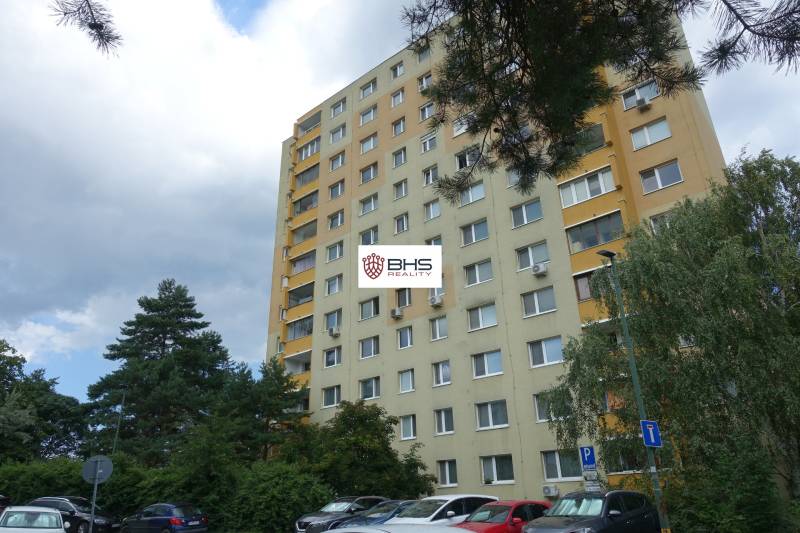 An apartment building in Bratislava-Dúbravka on Homolova Street, surrounded by trees and a parking lot.
