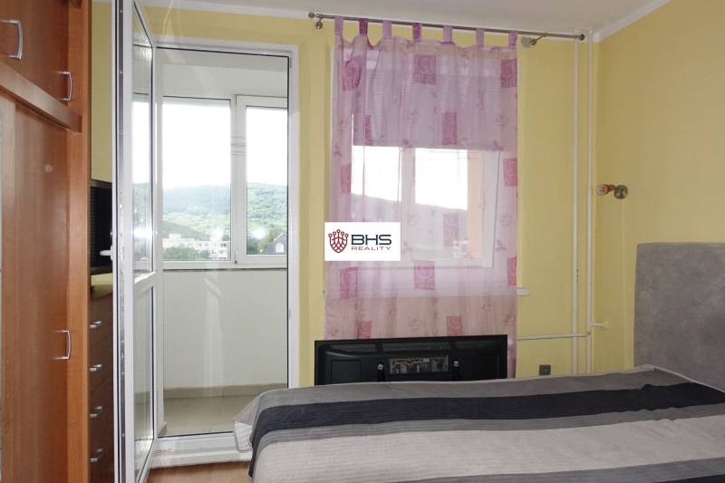 Bedroom with access to the balcony in a 3-room apartment with purple curtains on the window.