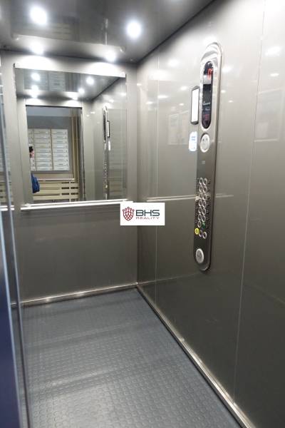 Interior of an elevator with a control panel and a mirror in a 3-room apartment.